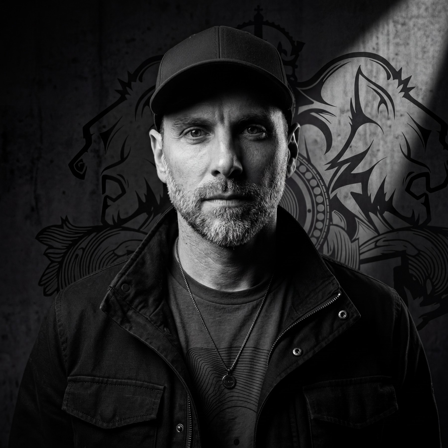 Black and white portrait of Fonkah in front of a graffiti wall